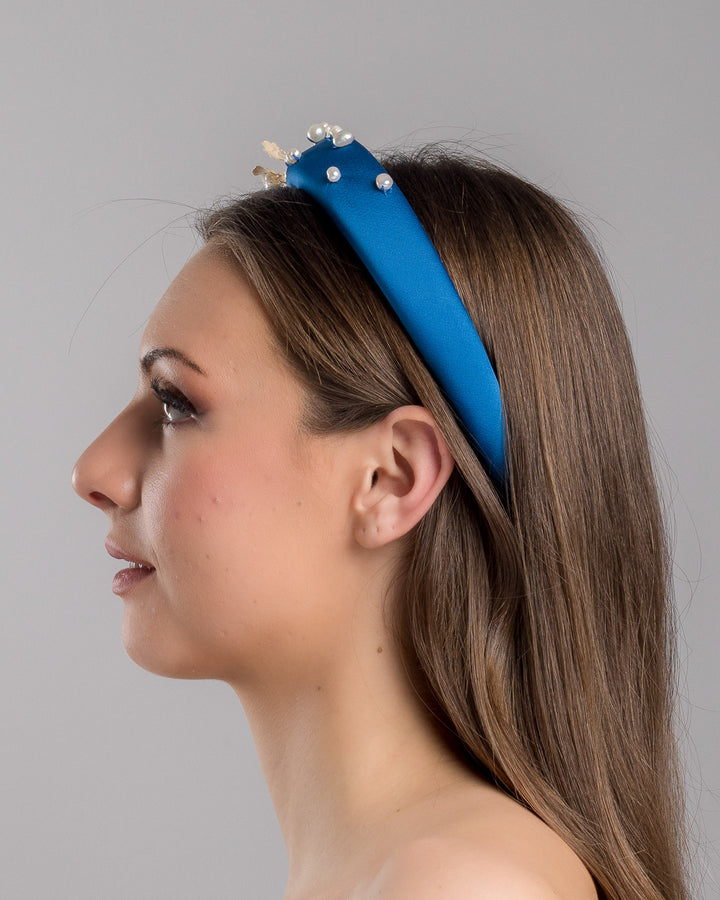 Model is showcasing the left side close up of teal silk sateen headband, a favourite yet hard to find colour decorated with mother of pearl wired flowers as well as mother pearl balls and beads. The pearl on the headband elevates the idea of a simple headband to a whole new level. Made by Merve Bayindir Millinery.