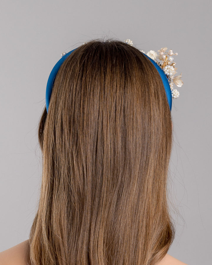 Model is showcasing the back side close up of teal silk sateen headband, a favourite yet hard to find colour decorated with mother of pearl wired flowers as well as mother pearl balls and beads. The pearl on the headband elevates the idea of a simple headband to a whole new level. Made by Merve Bayindir Millinery.