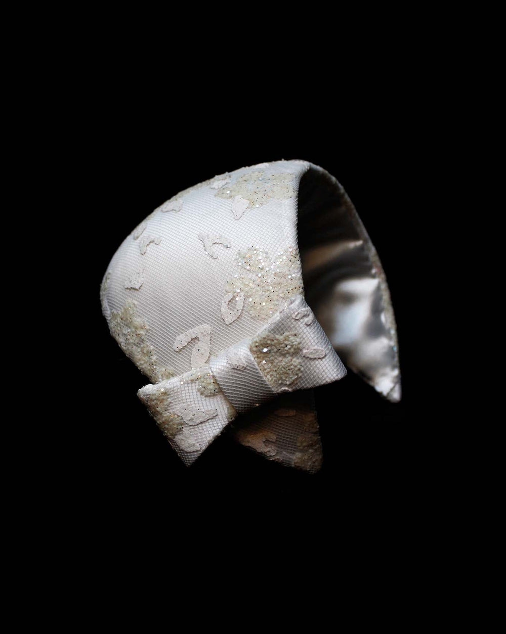 The half moon style white bridal headband decorated with off white sparkle clusters. Adorned with a bow in same detailing on one side.