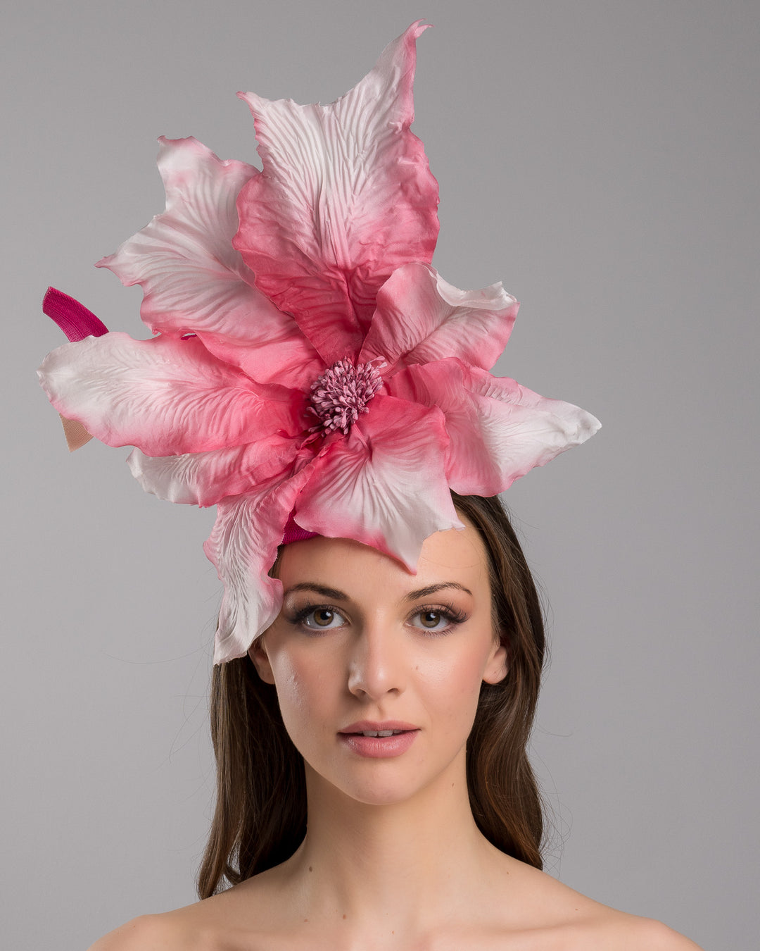 The model is showcasing the front side close up of the button shape Sinamay base decorated with custom made large silk chiffon flower and Jinsin swirls. Fitted with a wire headband and comb. Designed and made by Merve Bayindir Millinery.
