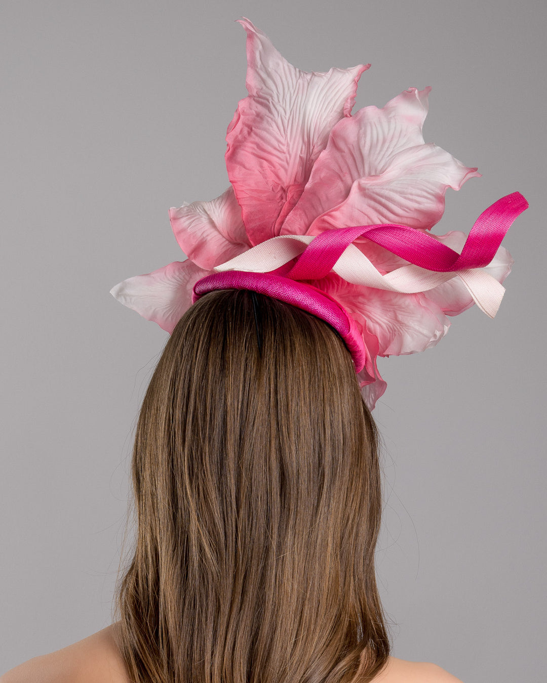The model is showcasing the back side close up of the button shape Sinamay base decorated with custom made large silk chiffon flower and Jinsin swirls. Fitted with a wire headband and comb. Designed and made by Merve Bayindir Millinery.

