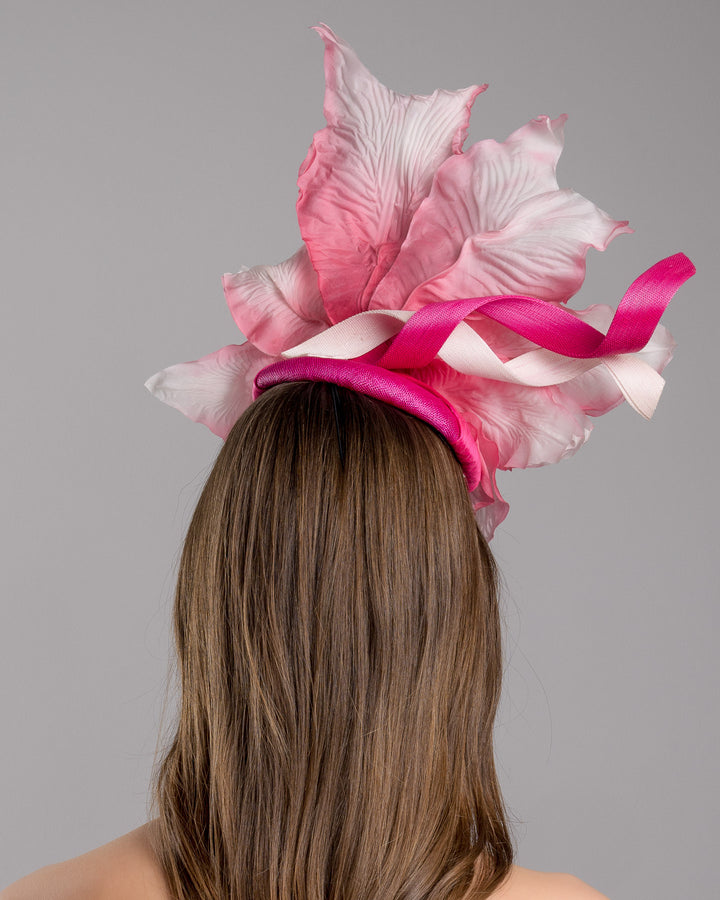 The model is showcasing the back side close up of the button shape Sinamay base decorated with custom made large silk chiffon flower and Jinsin swirls. Fitted with a wire headband and comb. Designed and made by Merve Bayindir Millinery.

