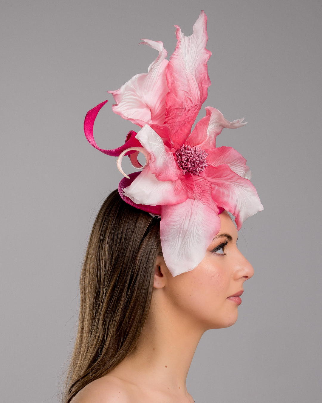 The model is showcasing the right side close up of the button shape Sinamay base decorated with custom made large silk chiffon flower and Jinsin swirls. Fitted with a wire headband and comb. Designed and made by Merve Bayindir Millinery.
