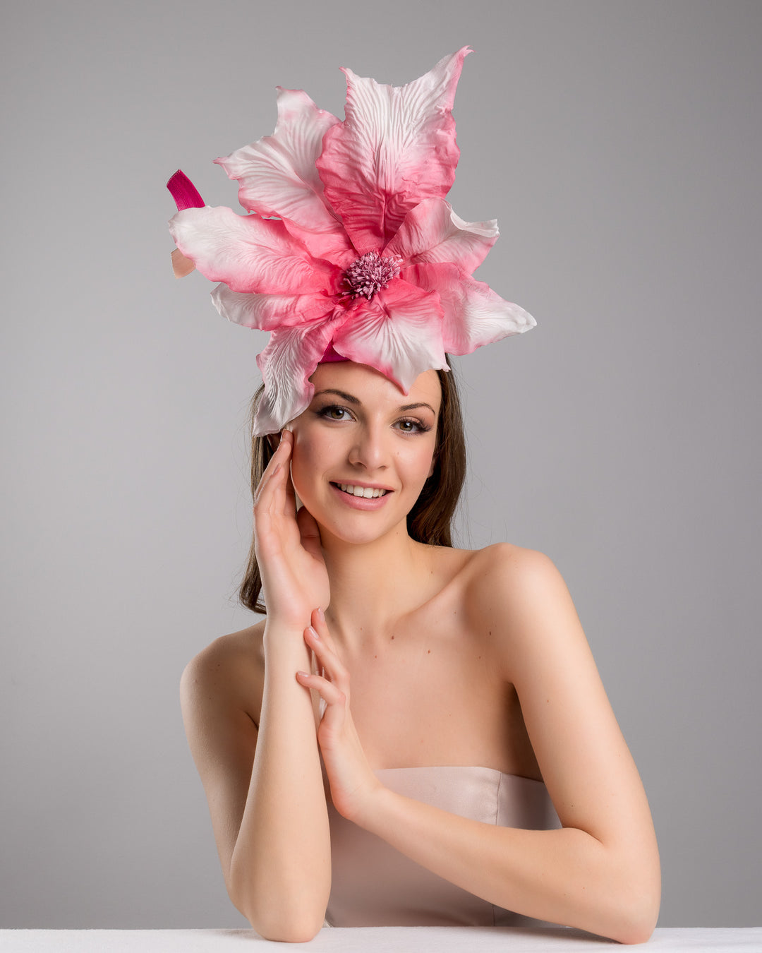 The female model is posing, wearing
Ischia, the button shape Sinamay base decorated with custom made large silk chiffon flower and Jinsin swirls. Fitted with a wire headband and comb. Designed and made by Merve Bayindir Millinery.
