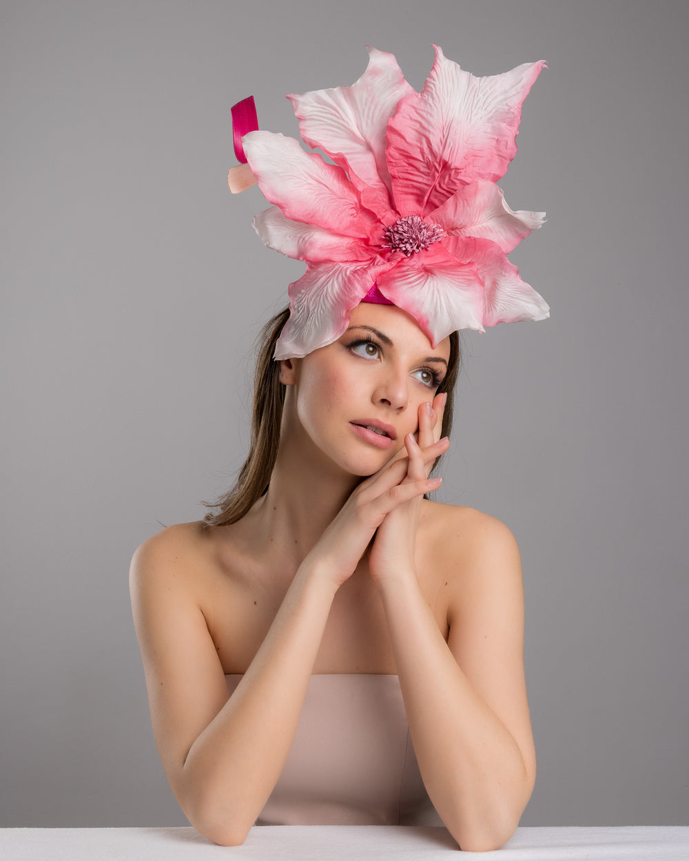 The female model is posing, wearing
Ischia, the button shape Sinamay base decorated with custom made large silk chiffon flower and Jinsin swirls. Fitted with a wire headband and comb. Designed and made by Merve Bayindir Millinery.
