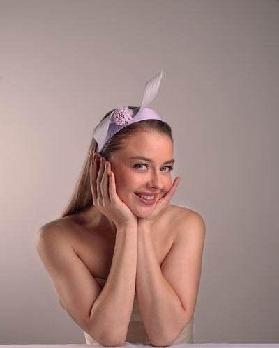 Model is showcasing a silk flat Alice style lilac headband, decorated with a JinSin swirl and a lilac mini tulle ponpon