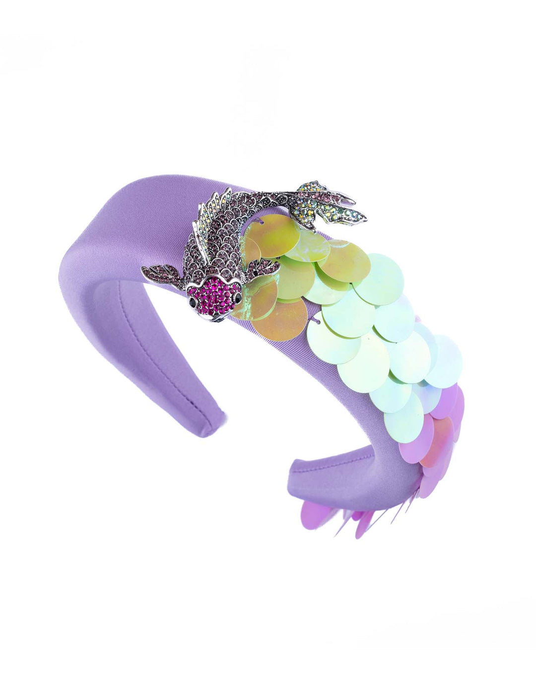 Still life picture of lilac headband embroidered with green and lilac sequins on one side and embellished with a metal koi fish with crystals. Made by Merve Bayindir Millinery.