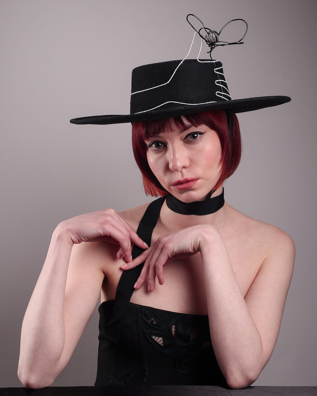 The model showcases the front of the Lune wide-brim boater hat, crafted in deep black felt, the hat&