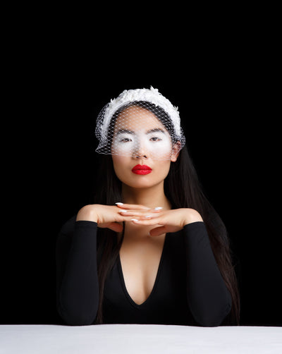 Model is showcasing a White bridal custom headband embroidered with flowers and silver beads with a veil.