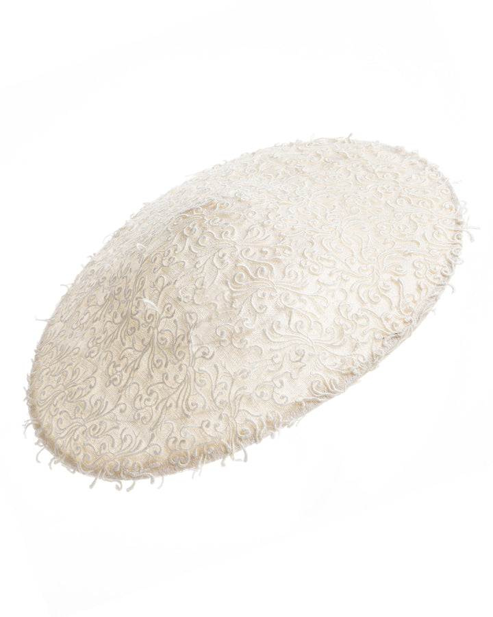 Still life picture of white coloured wide brim white hat embellished with lace swirls. Designed and Made by Merve Bayindir Millinery.
