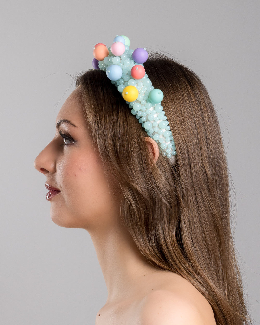 Model is showcasing the left side close up of multi size mint coloured beaded headband adorned with large multi size mat bubble look a like multi colour multi size beads. Made by Merve Bayindir.
