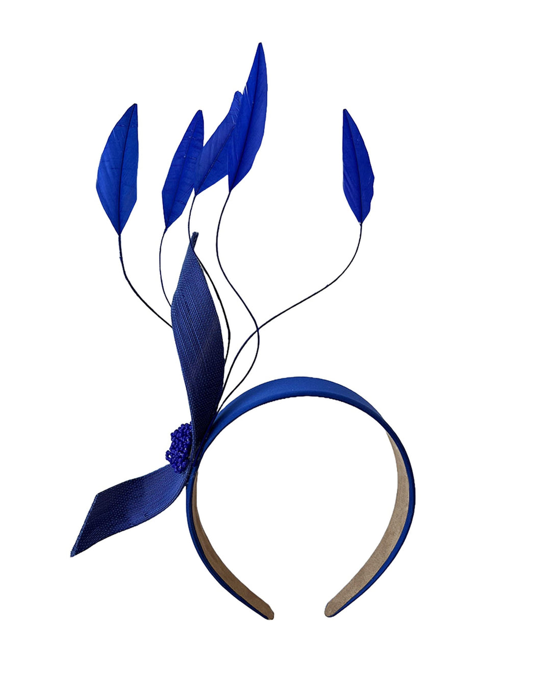 Still life picture of the Motmot headband fascinator crafted in a rich cobalt blue. This bold headband features a spray of sculpted feathers with hand-curved edges, accented with a swirl of buntal ribbon tied together with a beaded centre. Designed by Merve Bayindir.