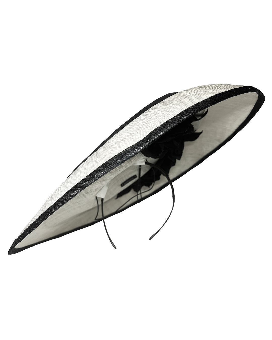 Wide black and white hat with an oversized flat brim, featuring a white woven top edged in black trim and finished with a black floral accent and slim headband for secure wear. Designed and made by Merve Bayindir MIllinery.

