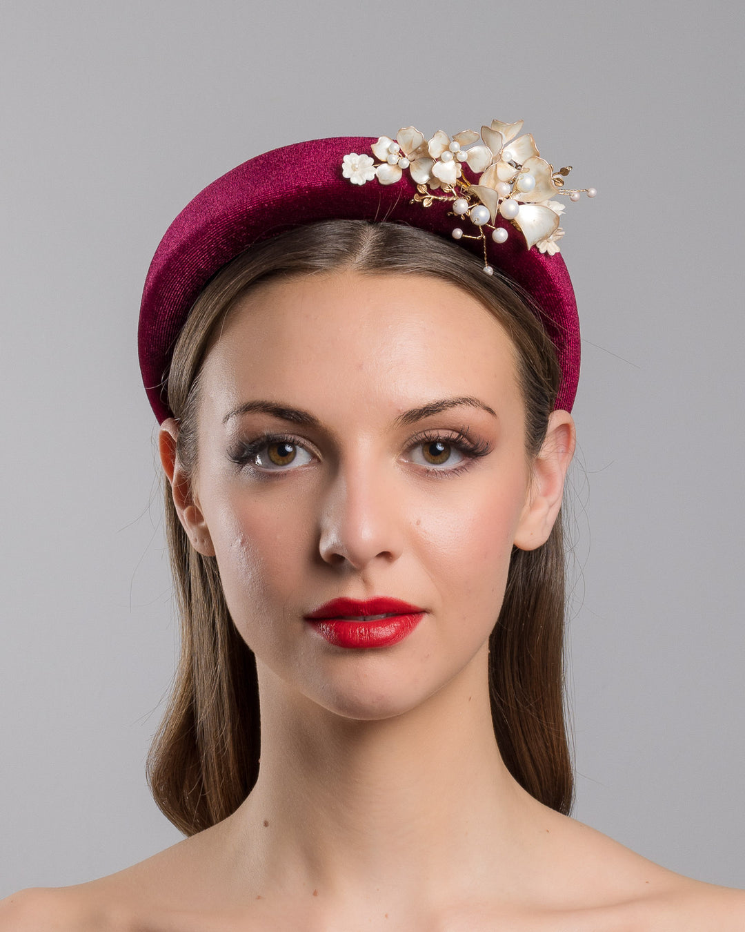 Model is showcasing the front of the high burgundy velvet headband decorated with pearl coloured wired bead and resin flowers. Made by Merve Bayindir millinery.