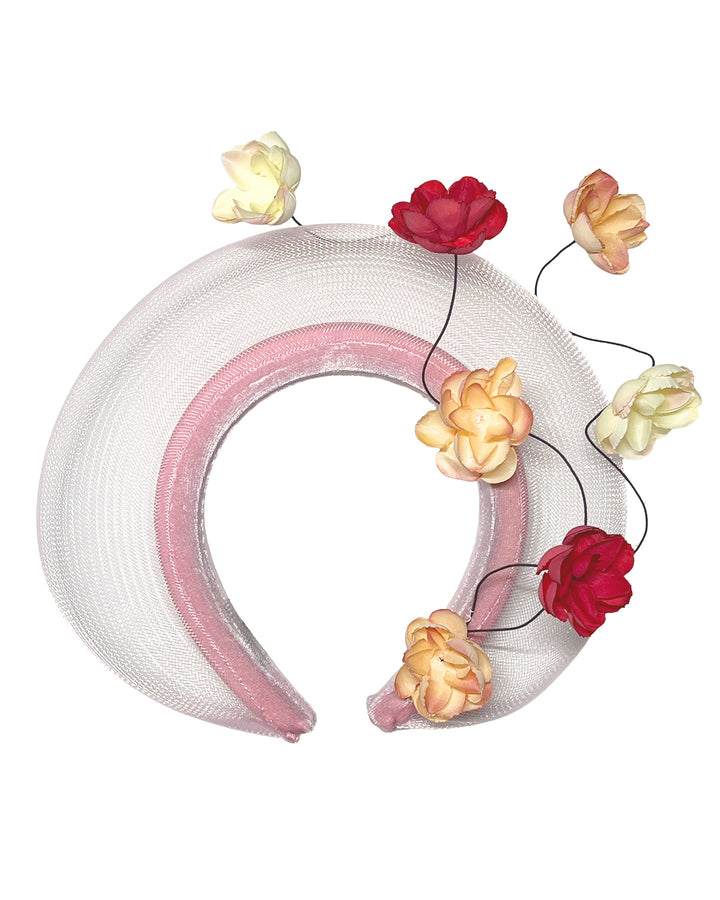 Blush pink headband fascinator with a sheer pale halo frame, adorned with wired floral embellishments in ivory, peach, and red tones. Designed and Made by Merve Bayindir millinery.