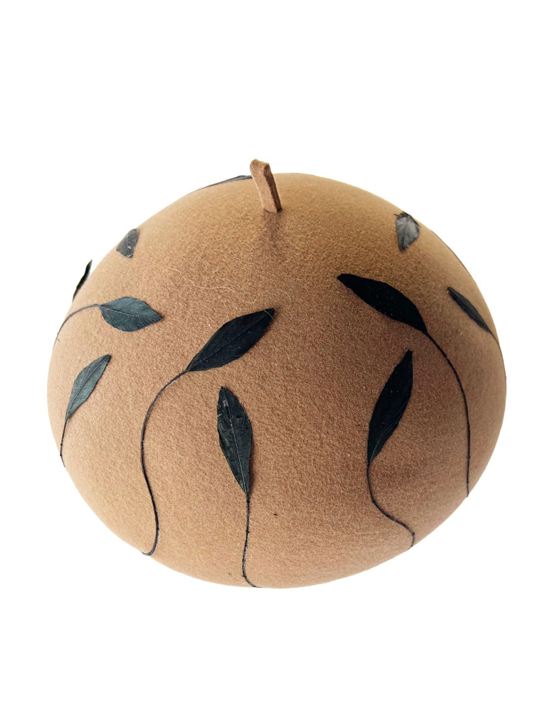 Still life picture of the Raven pillbox beret, crafted in warm caramel felt. Its sculptural silhouette is softened by delicate, trimmed black feather appliqué lines cascading around the hat. Designed by Merve Bayindir.