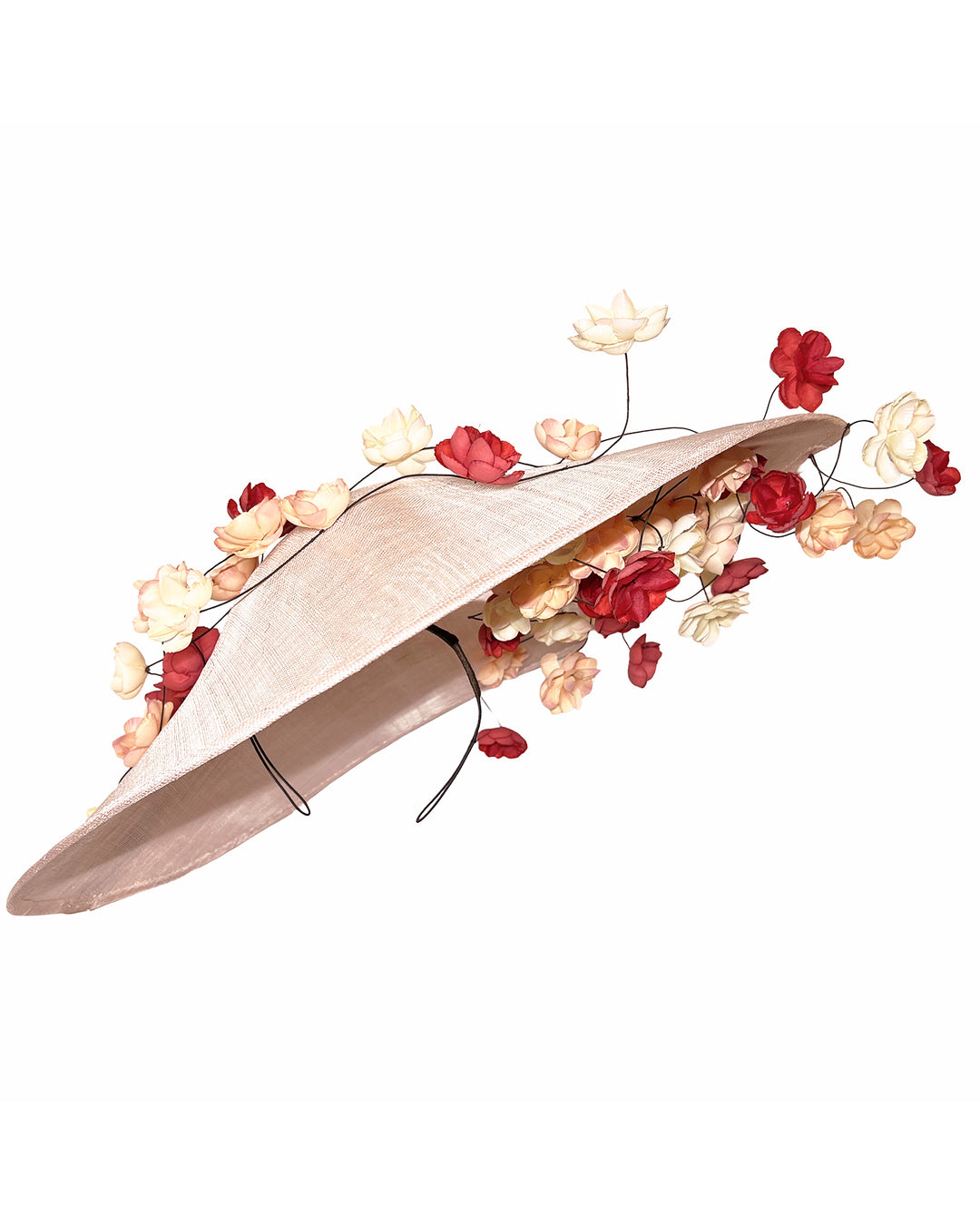 Soft blush sinamay base hat with an elegant sculpted brim, adorned with cascading clusters of cream, peach, and deep red flowers on fine wired stems, creating a romantic, floating garden effect. Designed and made by Merve Bayindir Millinery.
