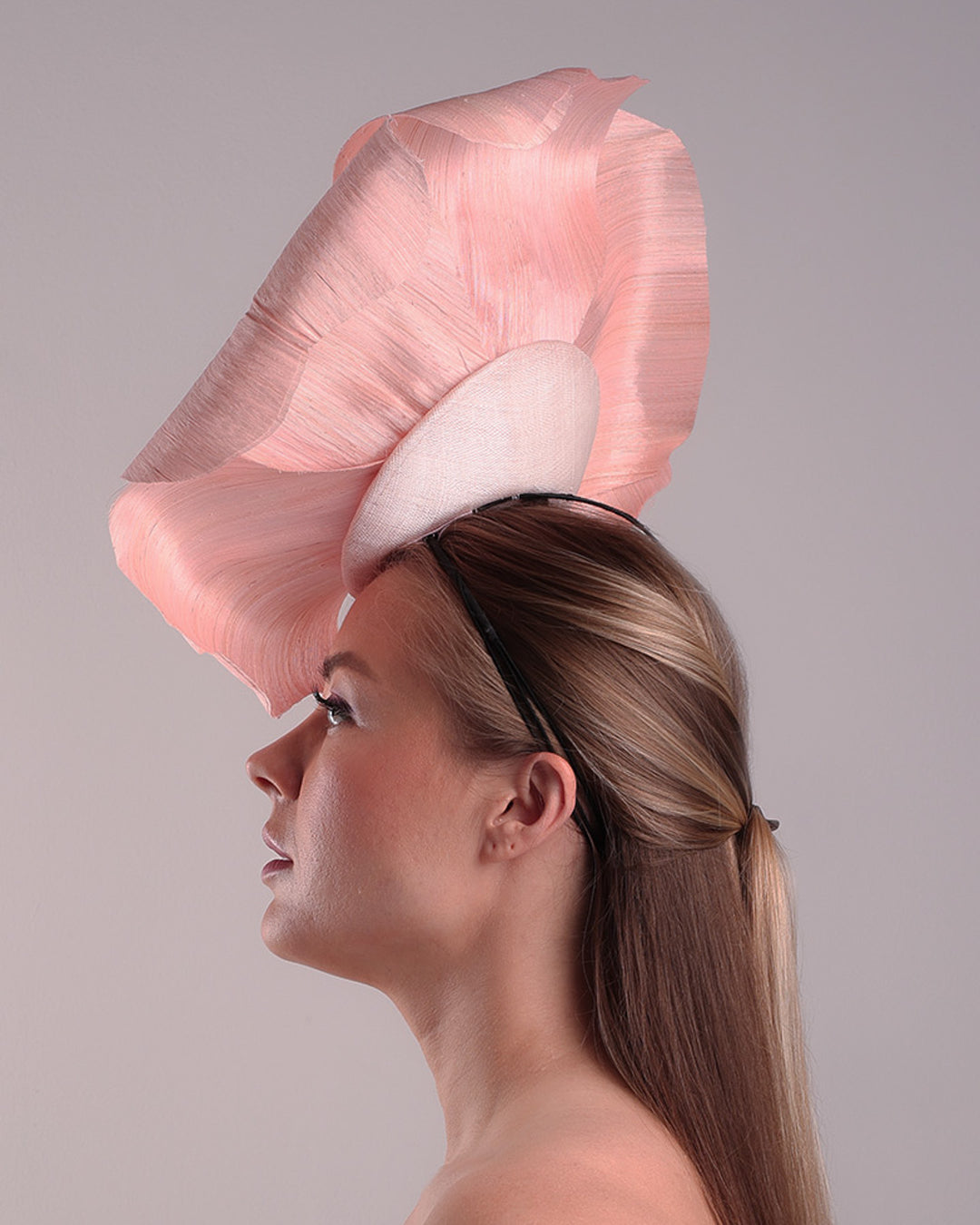 Model is showcasing the left side of an extra large light pink silk abaca flower centred towards the right side of the head. Fitted on a pink mini saucer style fascinator.