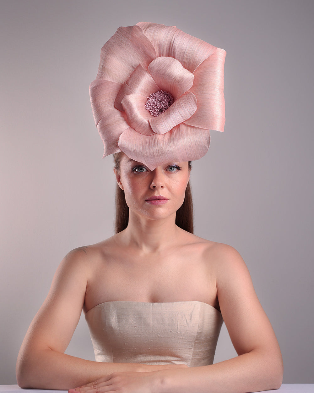 Model is showcasing the front angle of an extra large light pink silk abaca flower centred towards the right side of the head. Fitted on a pink mini saucer style fascinator.
