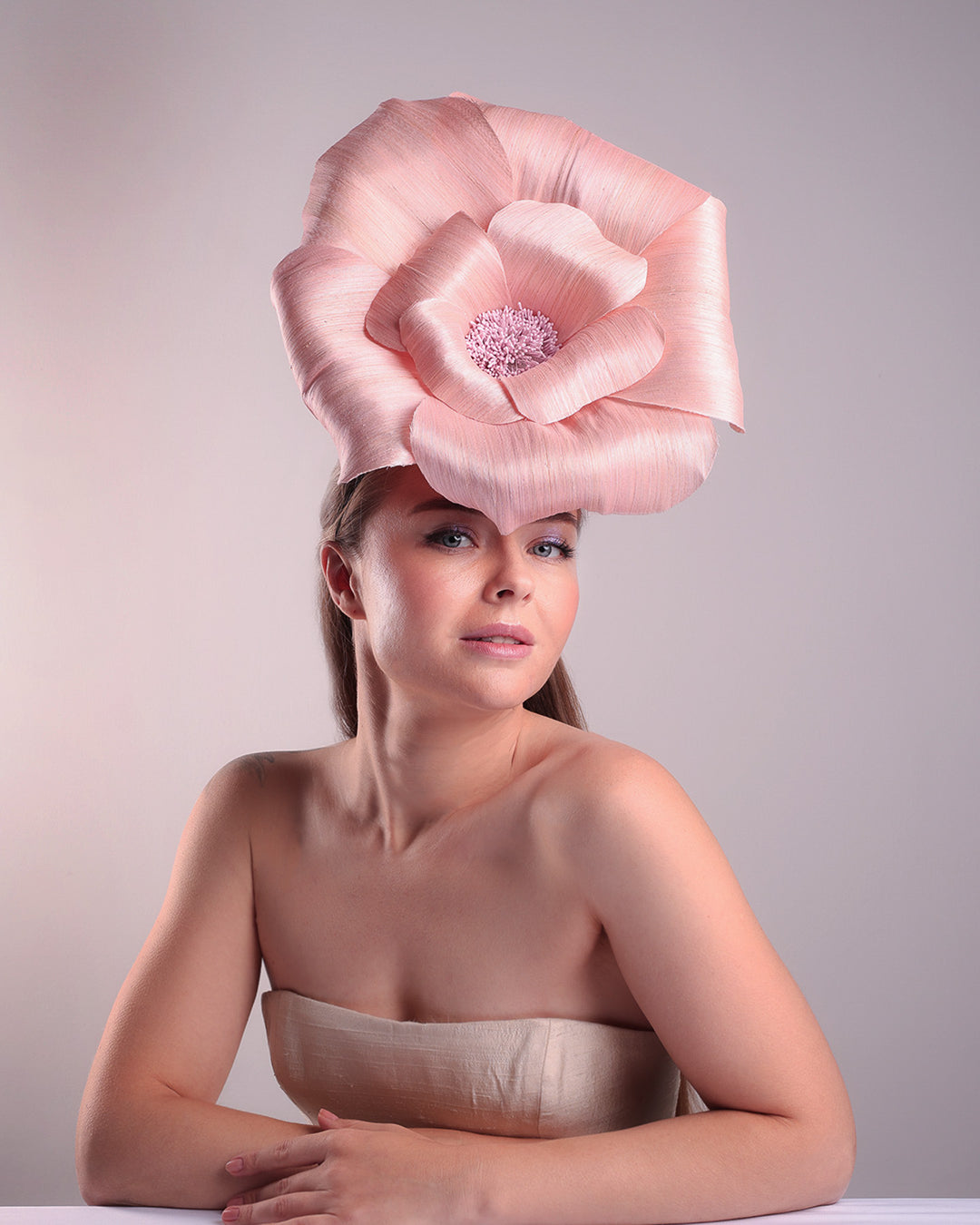 Model is showcasing the right front angle of an extra large light pink silk abaca flower centred towards the right side of the head. Fitted on a pink mini saucer style fascinator.