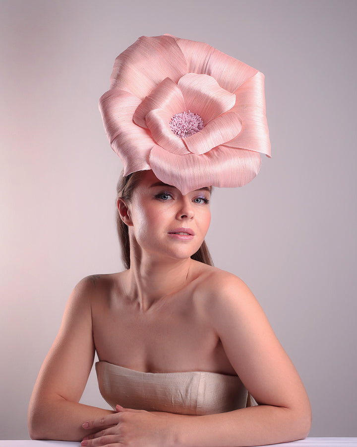 Model is showcasing the right front angle of an extra large light pink silk abaca flower centred towards the right side of the head. Fitted on a pink mini saucer style fascinator.