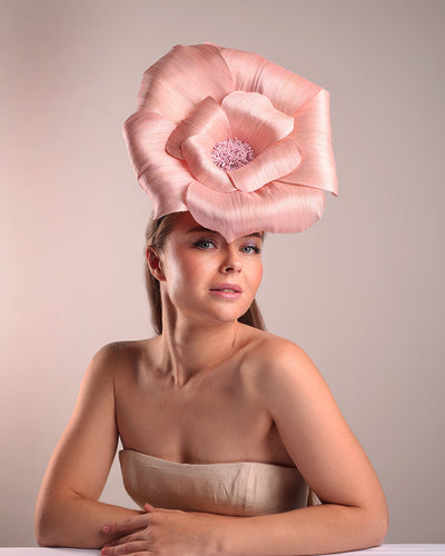 Model is showcasing the right front angle of an extra large light pink silk abaca flower centred towards the right side of the head. Fitted on a pink mini saucer style fascinator.