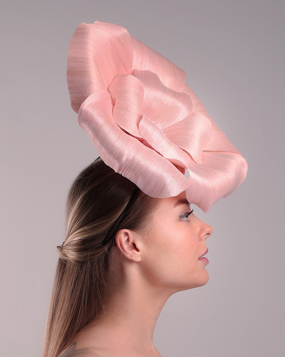 Model is showcasing the right side of an extra large light pink silk abaca flower centred towards the right side of the head. Fitted on a pink mini saucer style fascinator.