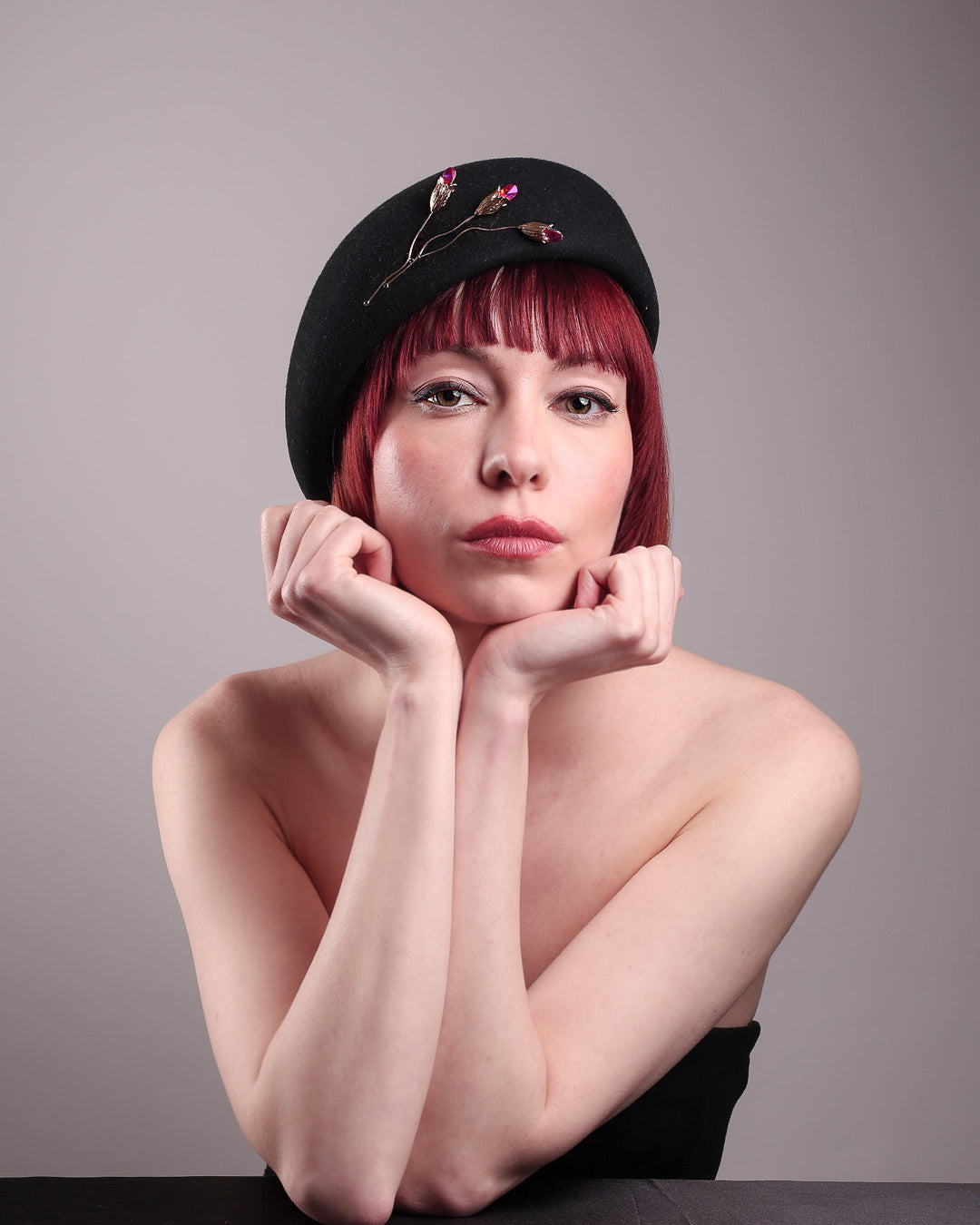 The female model is wearing a wool beret-style hat, showcasing the front view. The black hat is decorated with a real gold-plated brass metal branch motif adorned with crystal-tipped buds. The side beret is higher on the left side and shorter on the right side, and is suggested to be worn tilted. Designed by Merve Bayindir.
