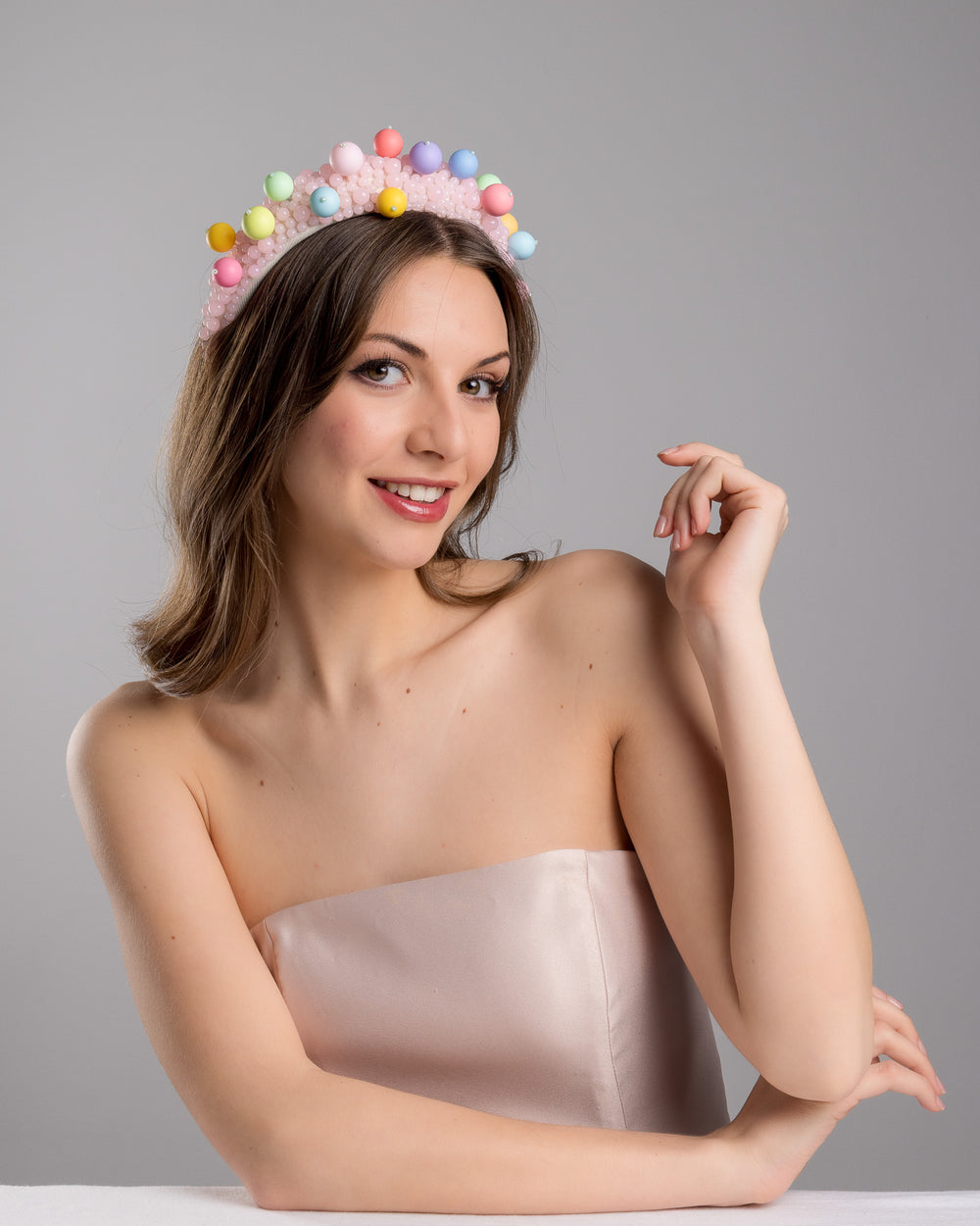 Female model posing wearing multi size pink beaded headband adorned with large multi size mat bubble look a like multi colour multi size beads. Mde by Merve Bayindir.