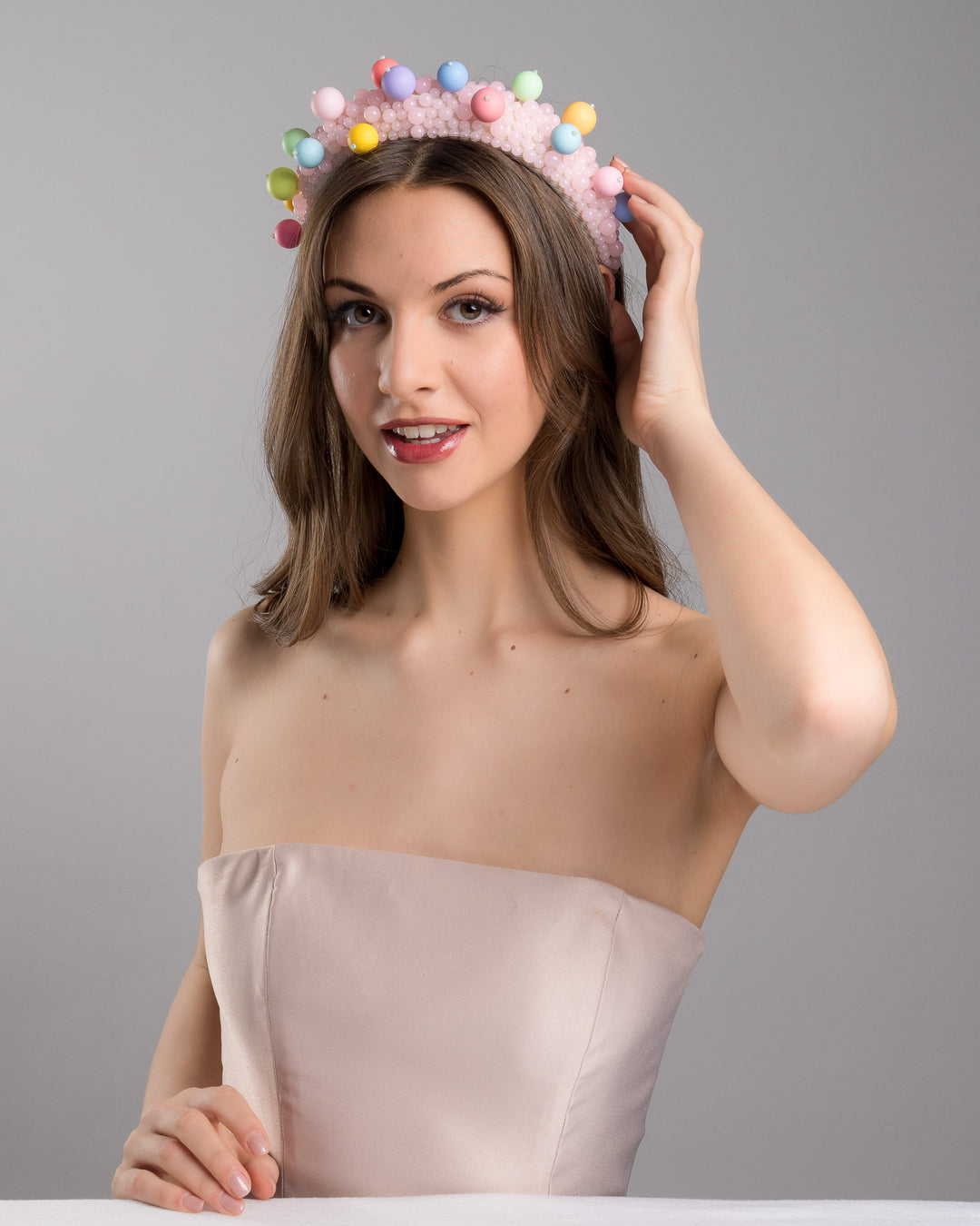 Female model posing wearing multi size pink beaded headband adorned with large multi size mat bubble look a like multi colour multi size beads. Mde by Merve Bayindir.
