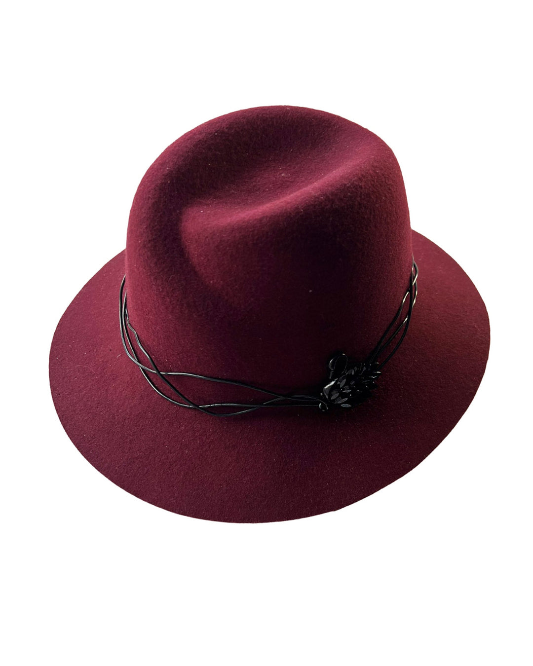 Still life picture of the Sylph fedora hat, a refined statement in deep burgundy felt, structured with clean, classic lines and softened by an ethereal twist: a fluid black wire detail weaves around the crown like delicate ink on parchment, with a crystal-embellished black metal swan on the left side. The embellishment feels both organic and intentional—a subtle nod to surrealism, grounded in wearable form.  Designed by Merve Bayindir.