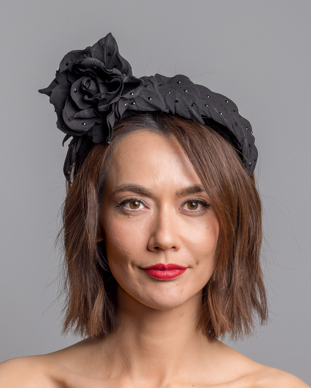 Model is showcasing the back side close up side of high lycra black headband, decorated with crepe rose and leafs embellished with crystals made by Merve Bayindir millinery.