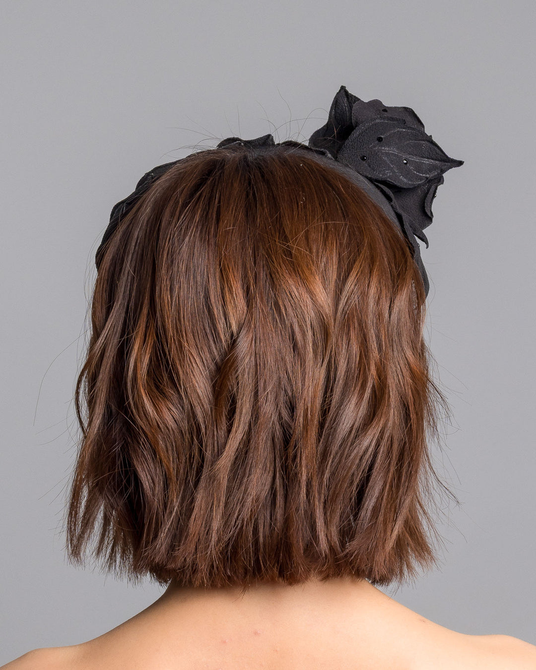 Model is showcasing the back side close up side of high lycra black headband, decorated with crepe rose and leafs embellished with crystals made by Merve Bayindir millinery.