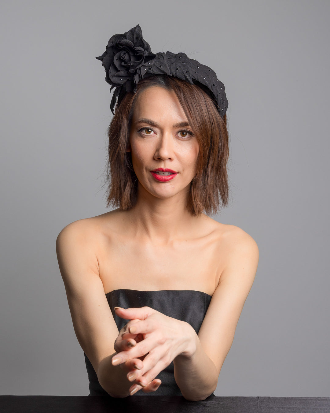 Female model is posing wearing Tango high lycra black headband, decorated with crepe rose and leafs embellished with crystals made by Merve Bayindir millinery.