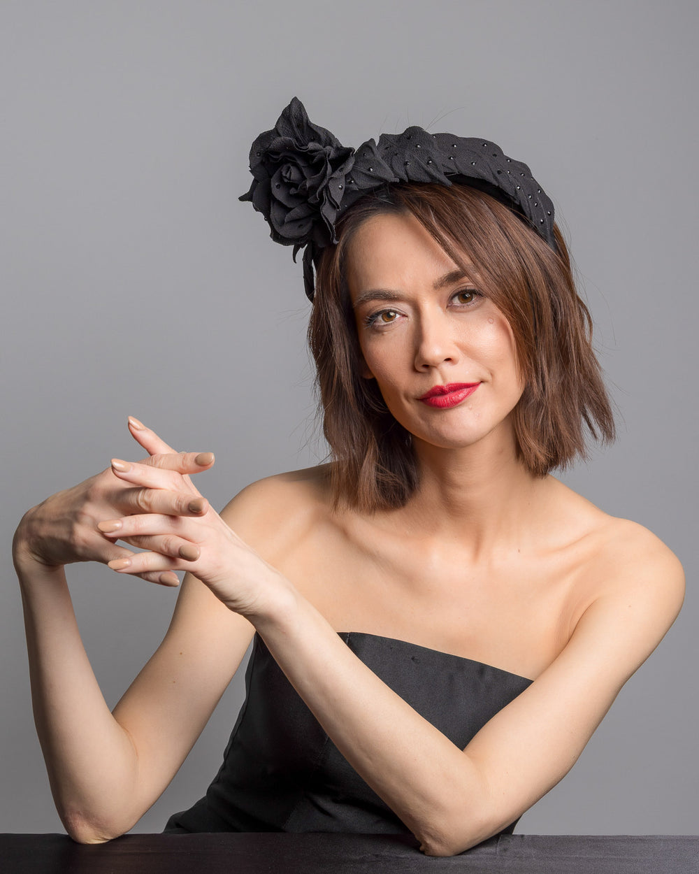 Female model is posing wearing Tango high lycra black headband, decorated with crepe rose and leafs embellished with crystals made by Merve Bayindir millinery.