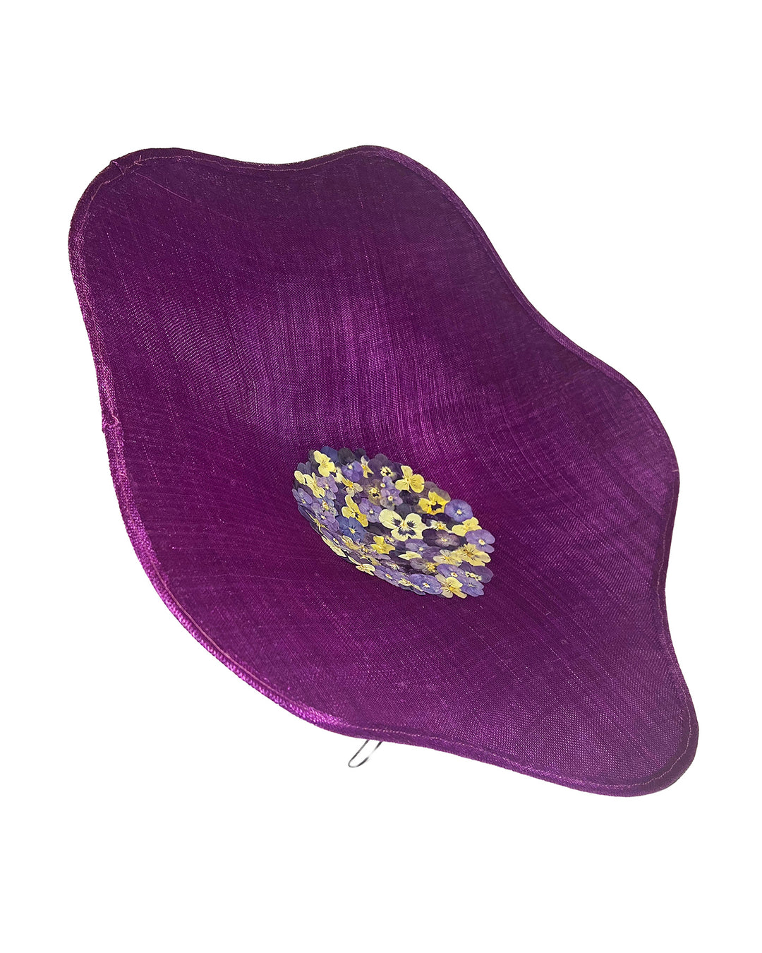Purple sinamay statement fascinator with an organically sculpted, flowing silhouette, featuring a central cluster of delicate yellow and violet flowers for a vibrant, artistic finish. Designed and made by Merve Bayindir Millinery.
