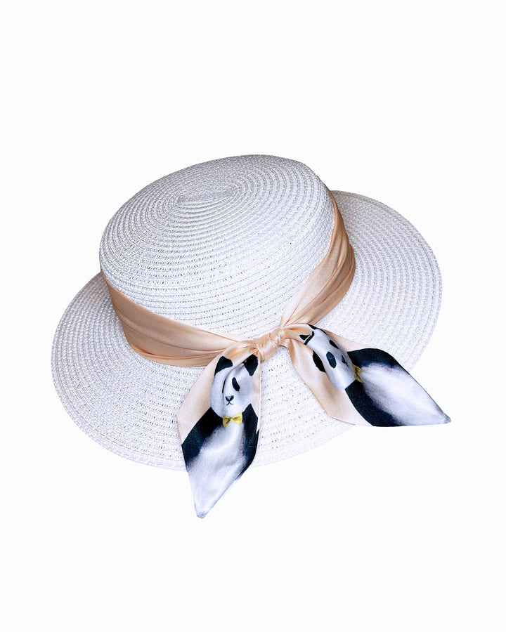 White woven straw boater hat with a wide brim, wrapped in a soft beige silk ribbon and finished with a tied scarf featuring illustrated panda motifs at the side. Designed and Made by Merve Bayindir millinery