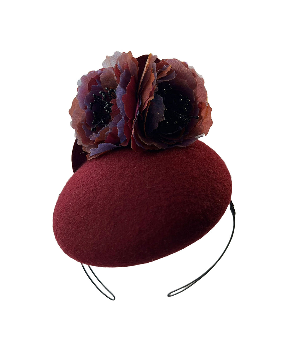 Still life photo of a burgundy felt pillbox fascinator with two handcrafted layered flowers in plum and bronze shades, featuring black bead centres, designed by Merve Bayindir.