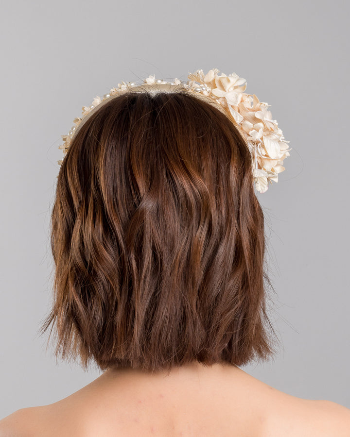 Model is showcasing the back side close up of beige coloured silk sateen ivory headband decorated with ivory cotton flowers an ivory beads. Made by Merve Bayindir.