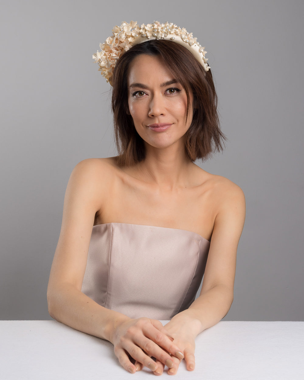 Model posing wearing Waltz beige coloured silk sateen ivory headband decorated with ivory cotton flowers an ivory beads. Made by Merve Bayindir.