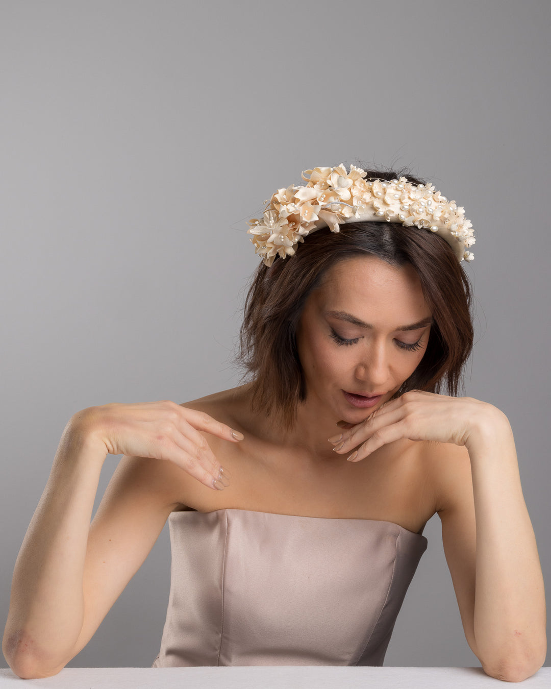 Model posing wearing Waltz beige coloured silk sateen ivory headband decorated with ivory cotton flowers an ivory beads. Made by Merve Bayindir.