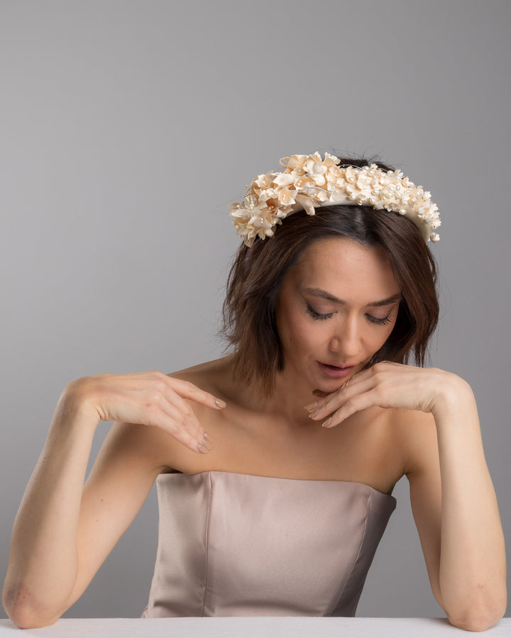 Model posing wearing Waltz beige coloured silk sateen ivory headband decorated with ivory cotton flowers an ivory beads. Made by Merve Bayindir.