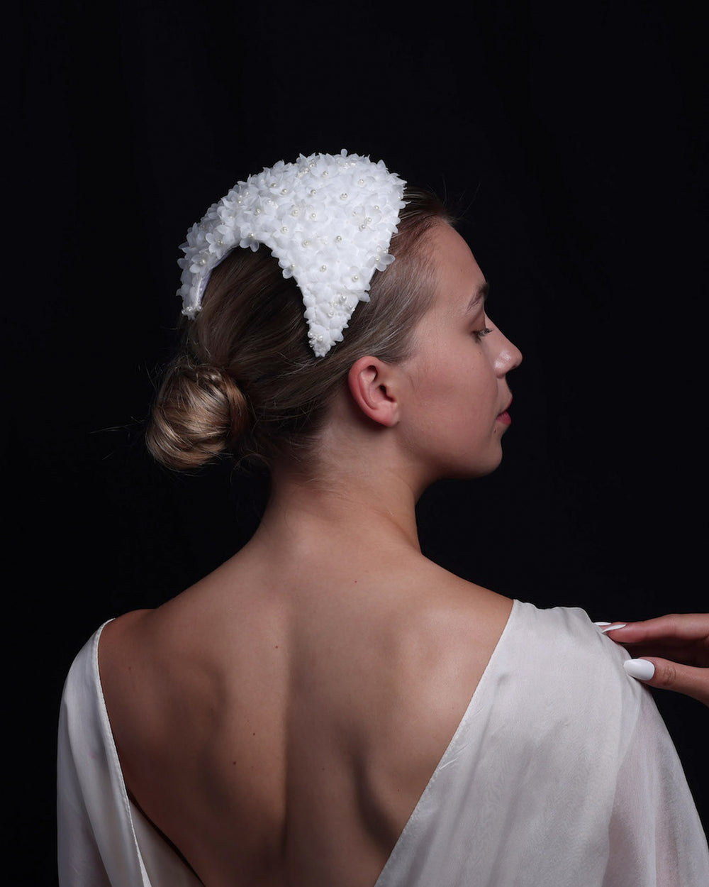  The model showcases the back of a custom-shaped bridal headpiece embellished with small organza flowers and pearl beads. The timeless headpiece brides.