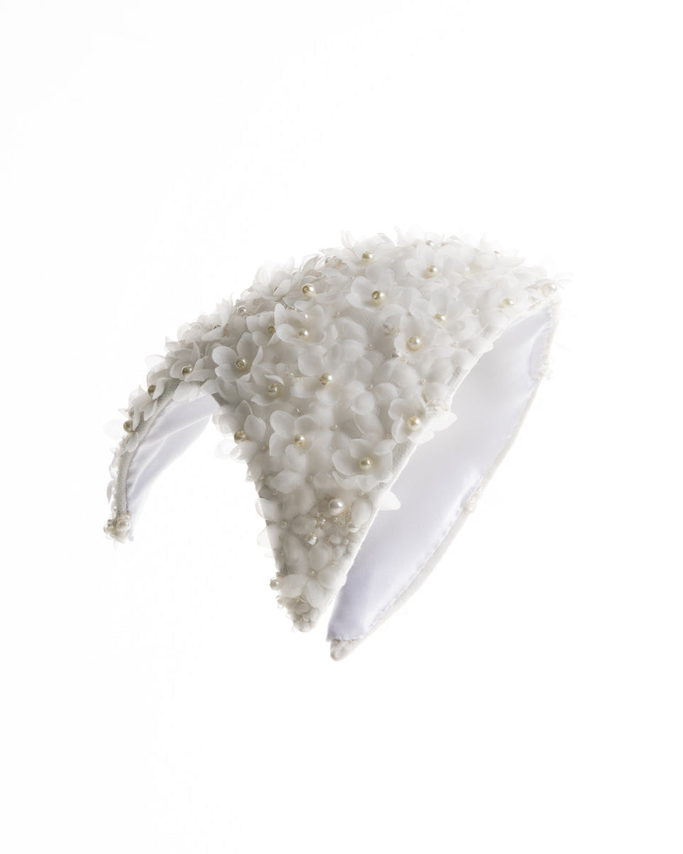 A custom shaped bridal headpiece embellished with small organza flowers and pearl beads.
