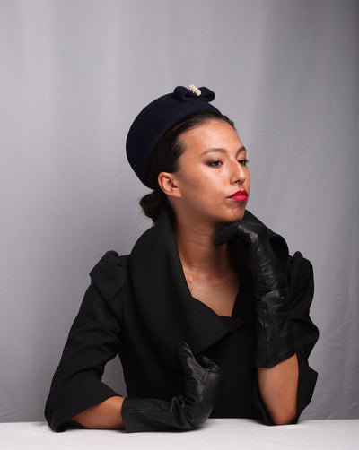 The model is wearing navy-coloured pillbox-style hat with a small navy felt bow embellished with cultured pearl balls.