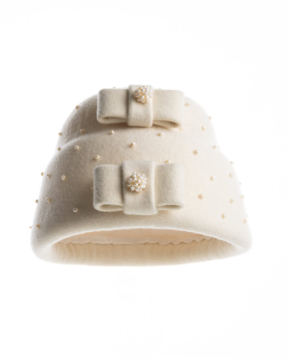The picture is a double layer, tall ivory pillbox hat embellished with pearls.. The hat has ove ivory felt bow on each later, centres adorned with pearl balls. 