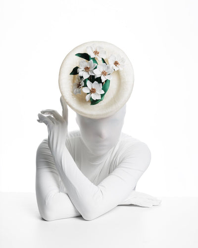 Oval shaped, ivory high saucer fascinator worn to the front centre&nbsp;of the head. Decorated with white silk flowers and green sateen leaves.