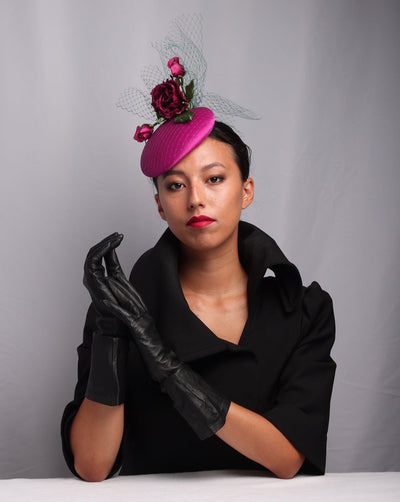 The model is wearing a pink button fascinator, sateen covered fascinator also covered with green veil and embellished with sateen roses. &nbsp;The green veil on top of the pink sateen gives a depth to the piece. Embellishing the hat with a large rose two rose buds a simple but elegant look. &nbsp;