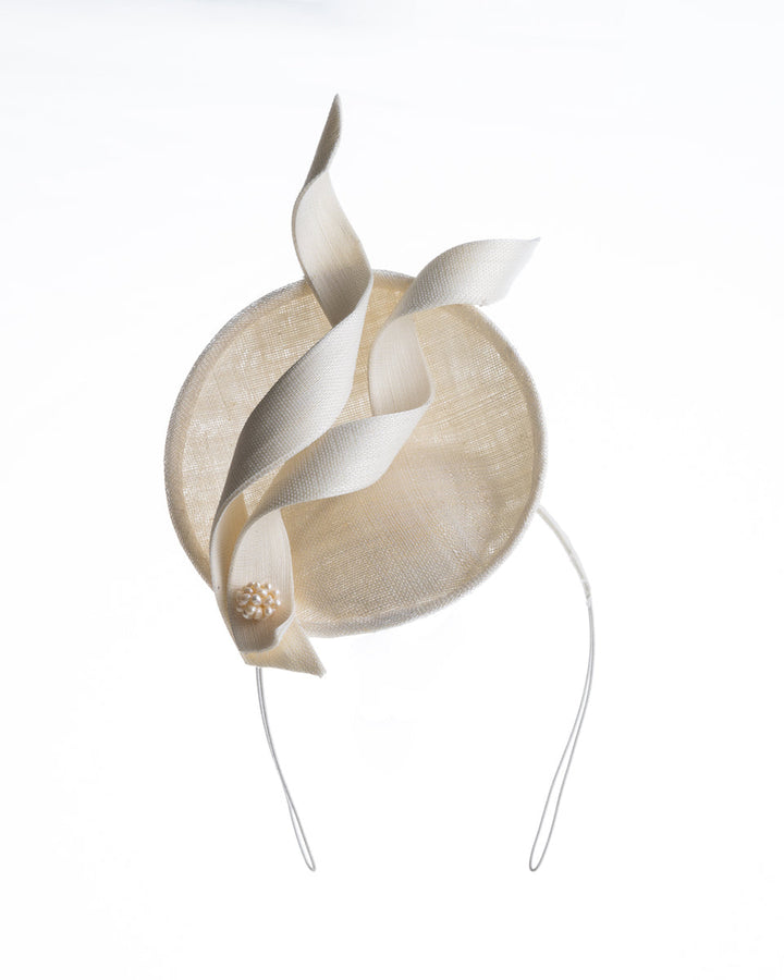 An off-white, mini saucer style fascinator decorated with two buntal swirls and a mother of pearl ball.