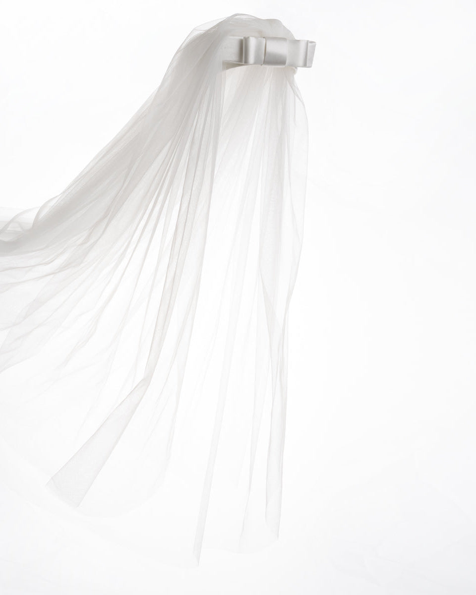 A short white sateen headband decorated with a double layered sateen bow and completed with a two-pieced ghost tulle veil.